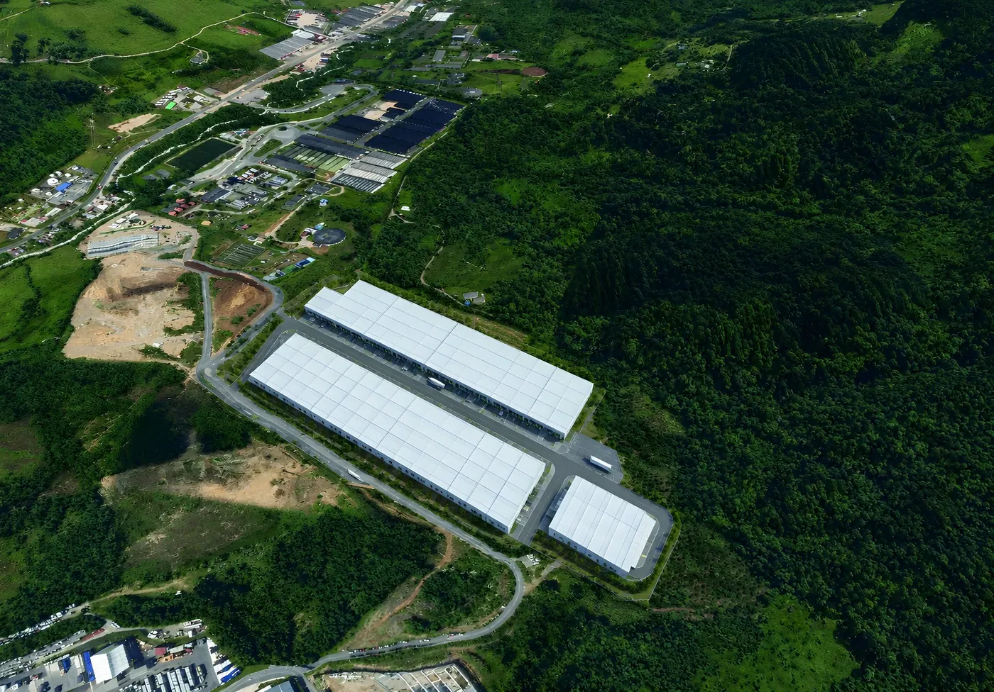 Render del CLIM visto desde arriba: tres bloques de bodegas y la v&iacute;a que los rodea, en medio del bosque
